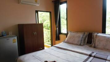 Quarto de hotel com cama, guarda-roupa, ar condicionado e janela com cortinas.