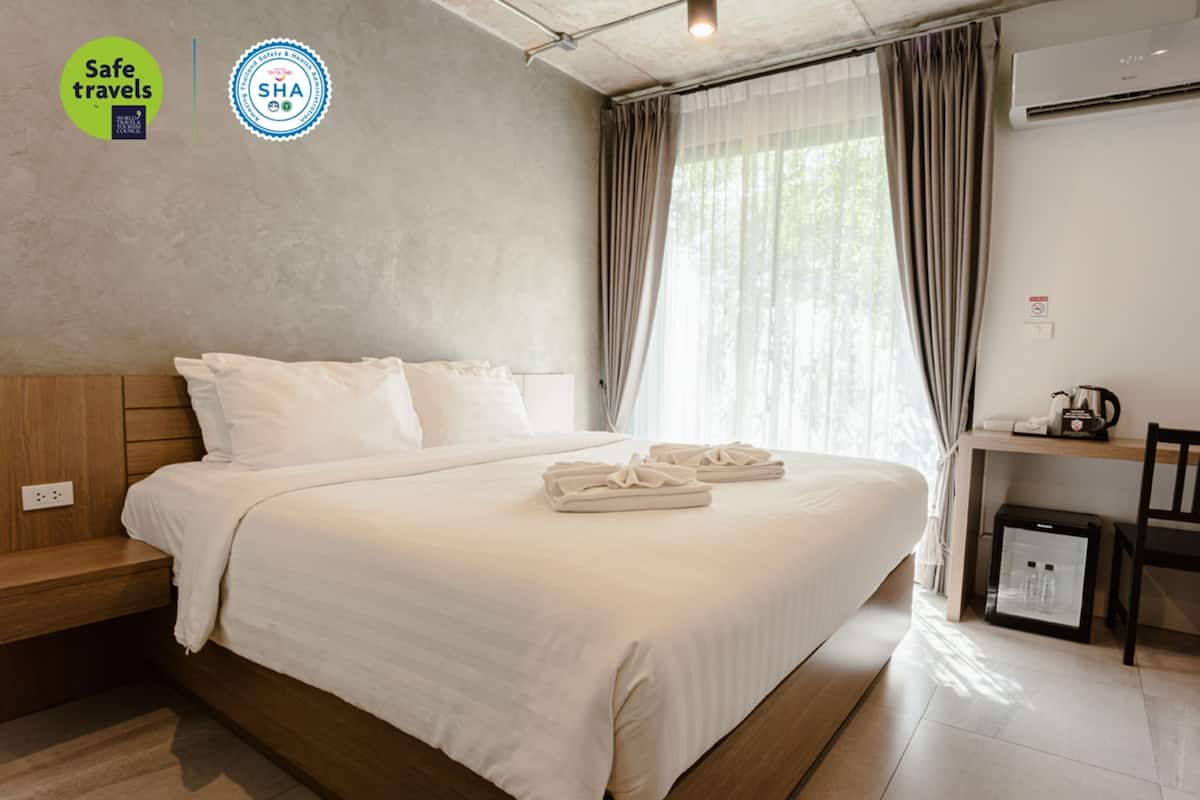 A hotel room with a bed, a desk, and a refrigerator.