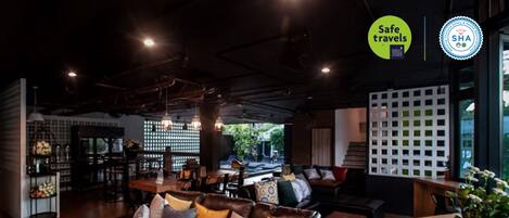 A modern lounge area with leather sofas, wooden tables, and a bar area.