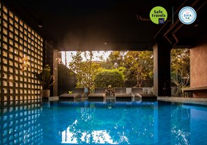 An indoor swimming pool with a view of trees and a brick wall. - The Echo Hotel (Chiang Mai)