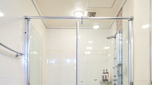 Ein modernes Badezimmer mit einer gläsernen Duschkabine, einem weißen Waschbecken und einem gefliesten Boden.
