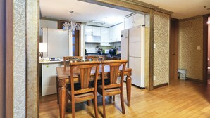 Ein Essbereich mit Holztisch und -stühlen, im Hintergrund eine Küche und Wandpapier mit Muster.