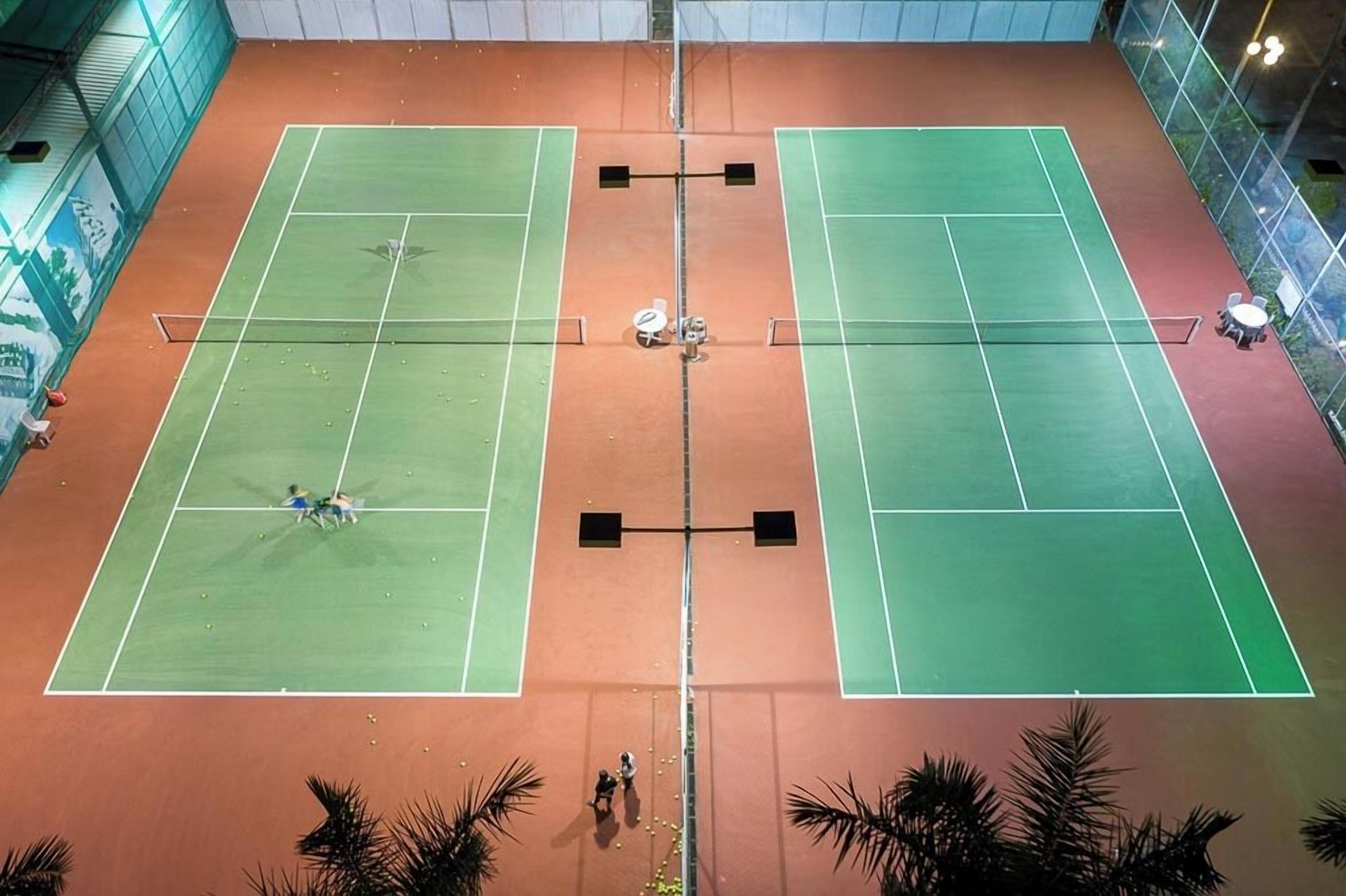 En indendørs tennisbane med to baner, et net og et siddeområde.