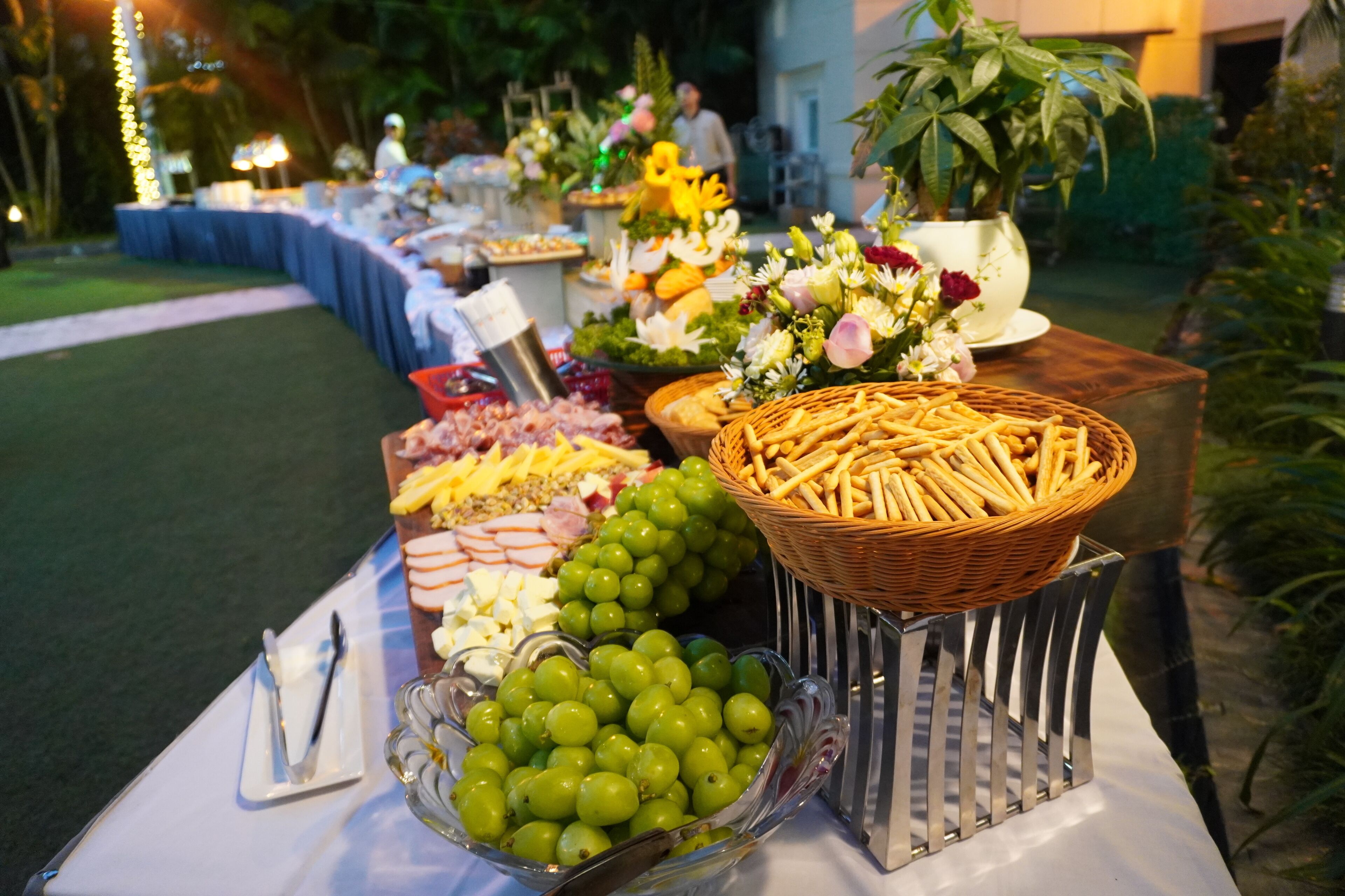 A buffet table with various food items and a decorative flower arrangement.