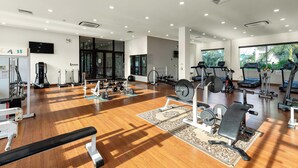 A spacious gym with various exercise equipment, large windows, and a wooden floor. - Sunflower International Village (Hai Phong)