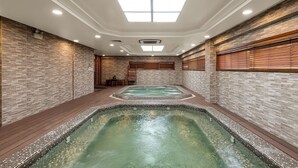 A spa area with two hot tubs, wooden flooring, and a tiled wall with a brick pattern. - Sunflower International Village (Hai Phong)