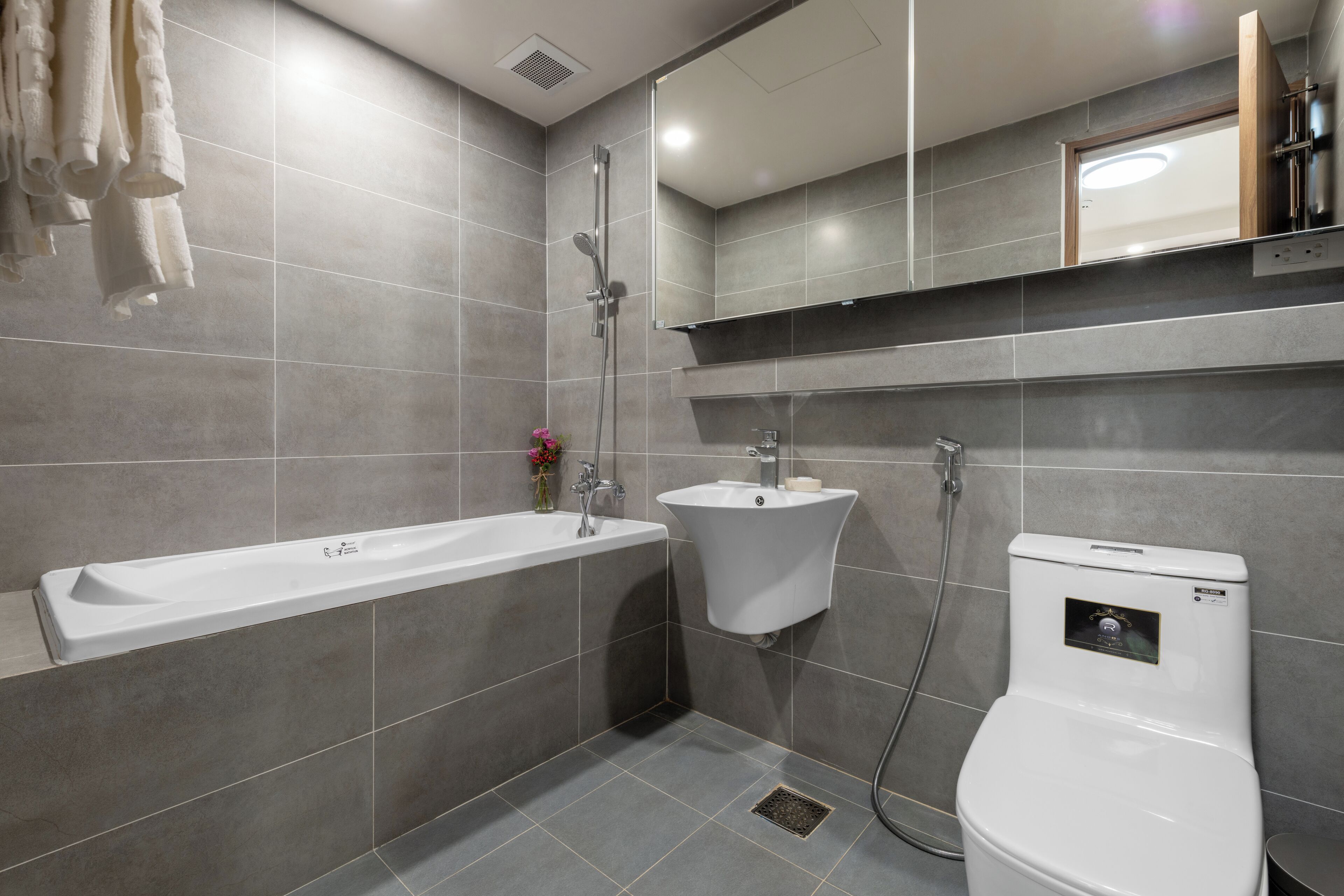 A modern bathroom with a bathtub, two sinks, and a toilet.