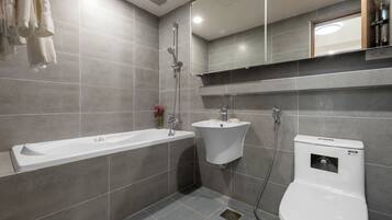 A modern bathroom with a bathtub, two sinks, and a toilet.