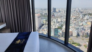 A hotel room with a large window offering a city view.