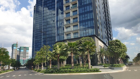Un edificio moderno de gran altura con fachada de vidrio, rodeado de palmeras y vegetación.