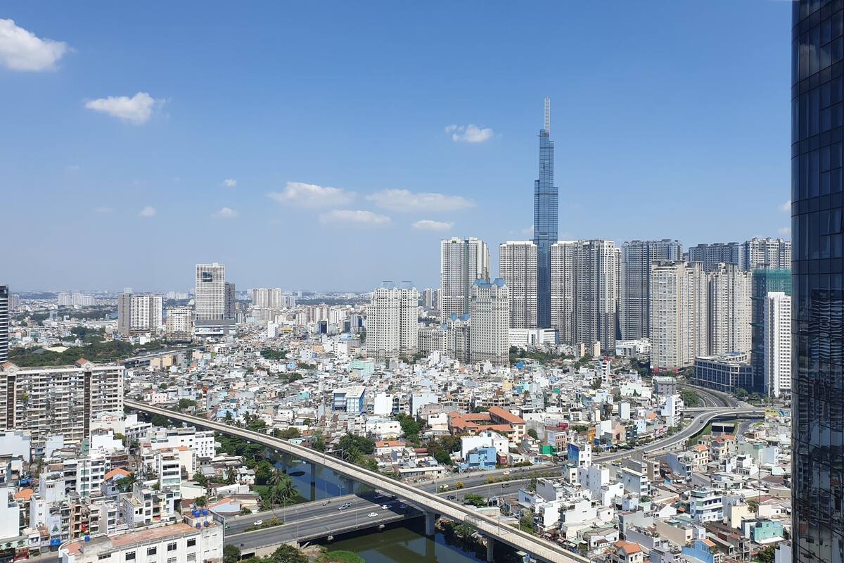 Un paysage urbain avec un gratte-ciel imposant, un pont et des immeubles d’habitation densément regroupés.