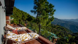 A balcony with two sun loungers, a railing, and a view of a mountainous landscape. - Seclude Kasauli (Kasauli)