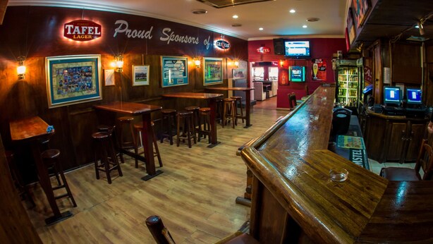 Un bar con muebles de madera, un letrero de Tafel Lager y cuadros en las paredes.