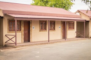 A building with numbered doors, a covered porch, and a metal roof. - Horseshoe Inn (Kimberley)