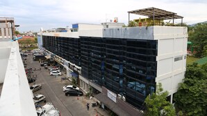 A multi-story building with a parking lot in front. - Jeune Hostel Chiang Mai (Chiang Mai)