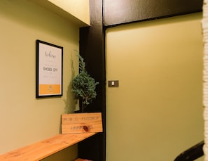 A hallway with a sign that says "Welcome, please take your shoes off, stay a while" and another sign that says "A,B,C floor > happiness". - Jeune Hostel Chiang Mai (Chiang Mai)