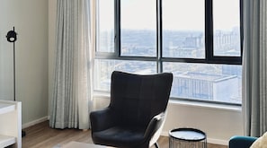 A room with a large window, a black armchair, a small round table, and a floor lamp. - Axis Luxury Apartments  by Century City Hotels (Cape Town)