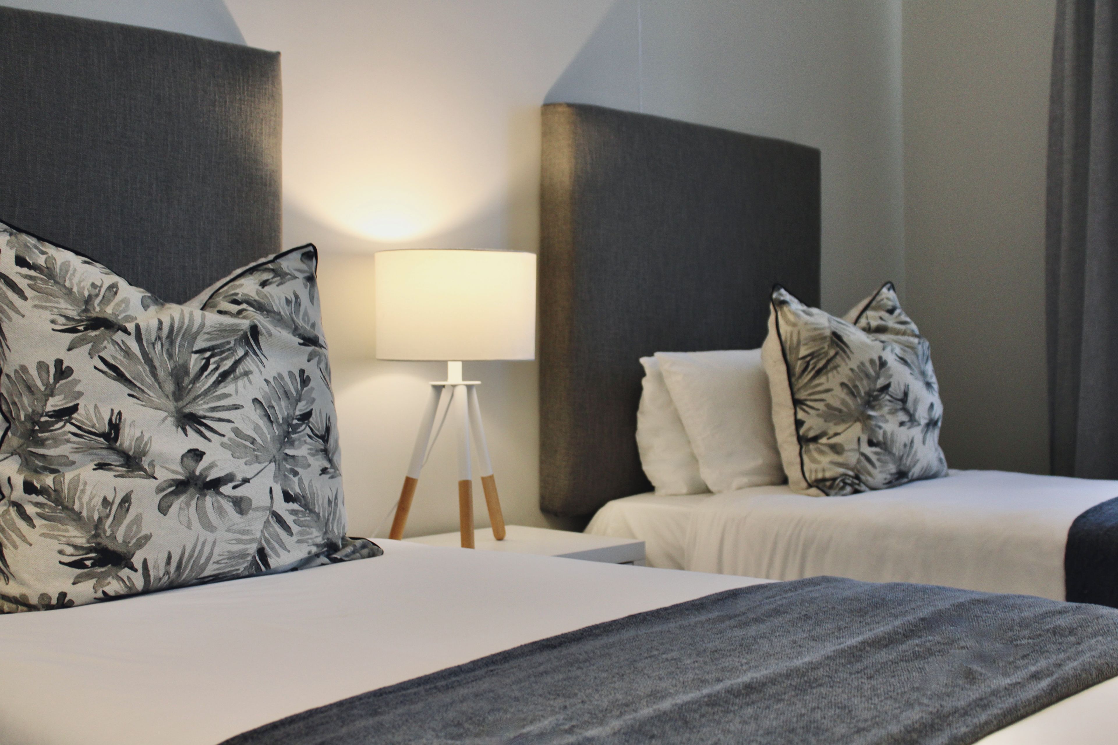 Une chambre d’hôtel avec un lit, une table de chevet, une lampe et un luminaire fixé au mur.