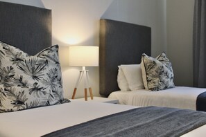 Een hotelkamer met een bed, een nachtkastje, een lamp en een wandlamp.