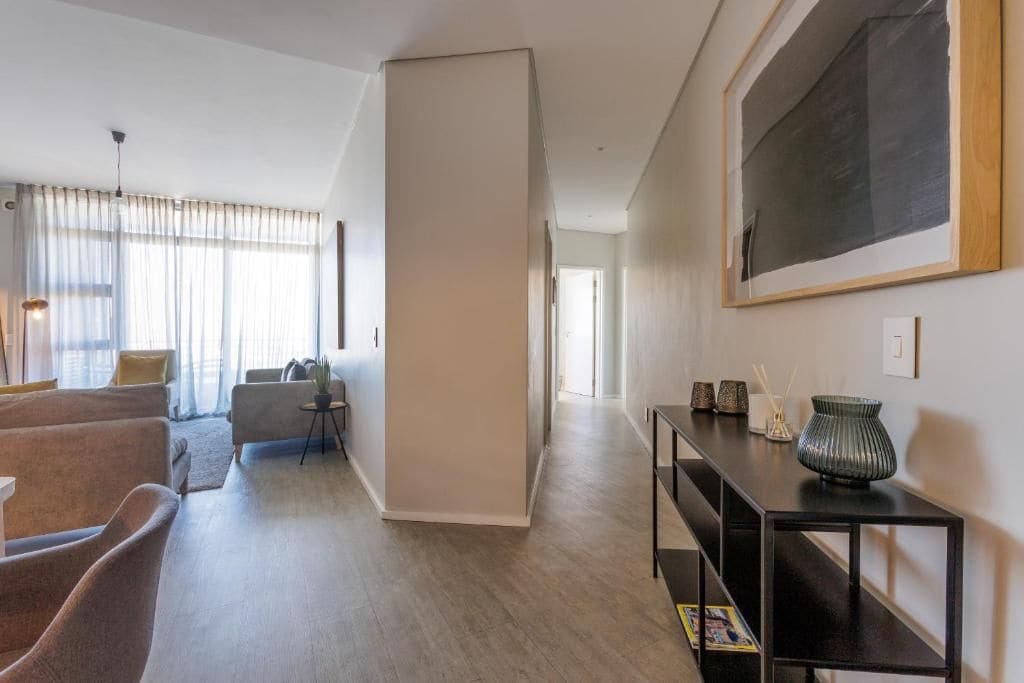 Uma sala de estar moderna com um sofá, uma mesa de centro e um espaço de jantar com um aparador preto.