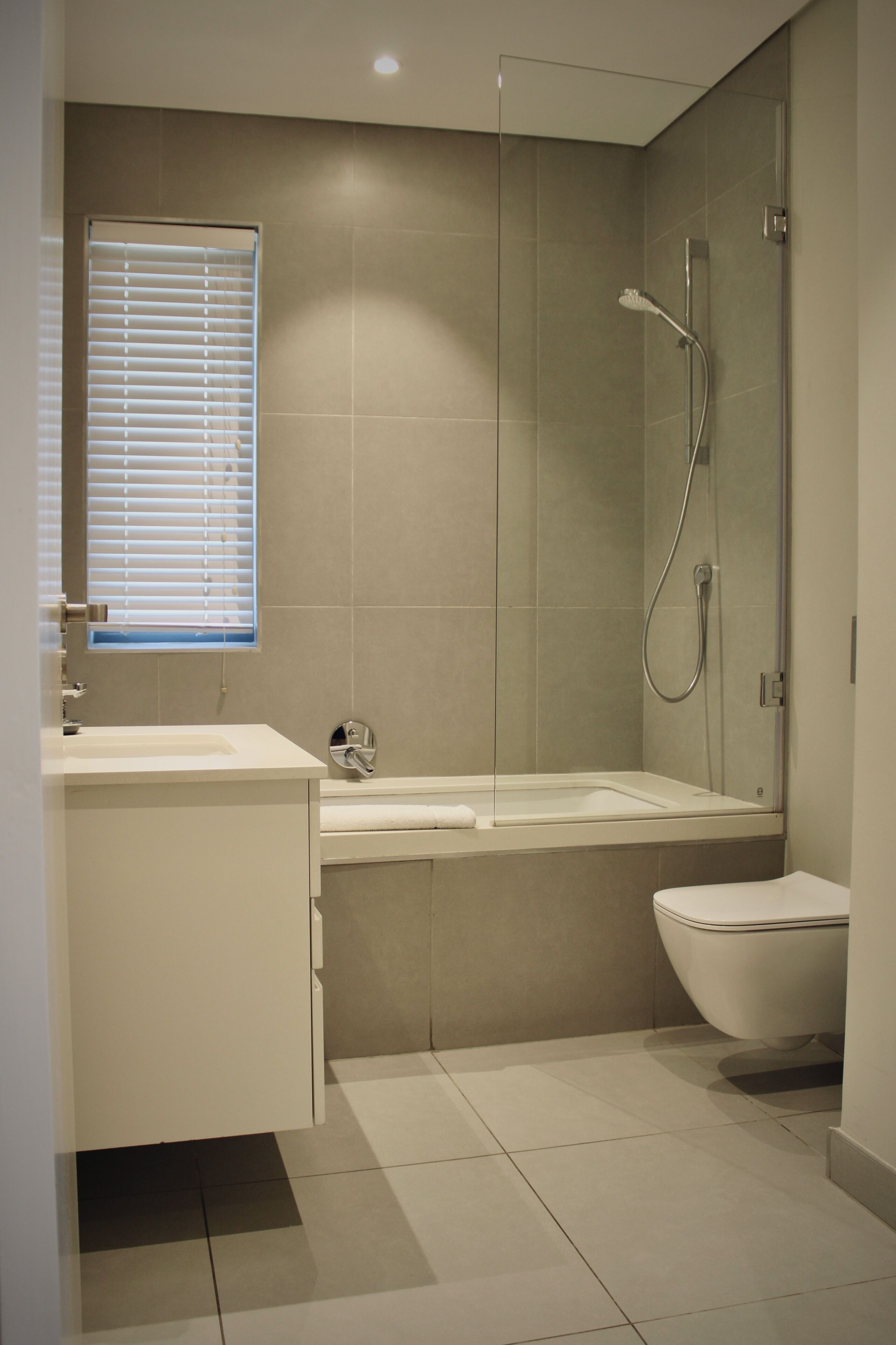 Un baño moderno con ducha envuelta en vidrio, un lavabo blanco y un inodoro.