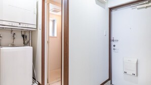 Une pièce avec un radiateur blanc, une porte dotée d’une poignée et un interrupteur sur le mur.
