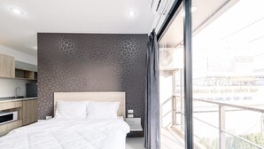 Un dormitorio moderno con una cama grande, una mesita de noche, un escritorio y vistas al exterior.