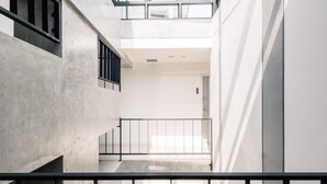 Un interior moderno con un espacio central abierto, paredes de concreto y techo de vidrio.