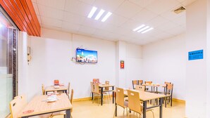 Une salle de conférence équipée de plusieurs tables et chaises, d’un téléviseur fixé au mur et d’un panneau indiquant la disponibilité du Wi-Fi.