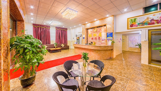 Un hall d’hôtel comprenant un comptoir d’accueil, un espace salon et une grande plante en pot.
