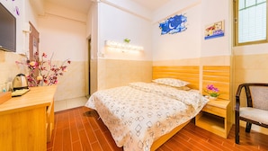 Une chambre d’hôtel équipée d’un lit, d’une table de chevet, d’une chaise et d’un téléviseur fixé au mur.