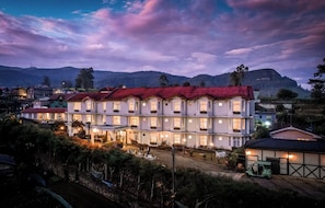 A multi-story hotel with a red roof, multiple balconies, and a well-lit entrance.