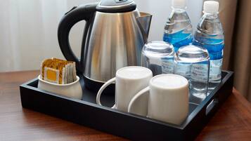 A tray with a stainless steel kettle, two white mugs, two water bottles, and a mug holder with cards.