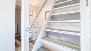A staircase with white railings and wooden steps, leading to a room with a white door and a light fixture above it. - tocoro. Mt. Fuji Hazuki (Fujikawaguchiko)