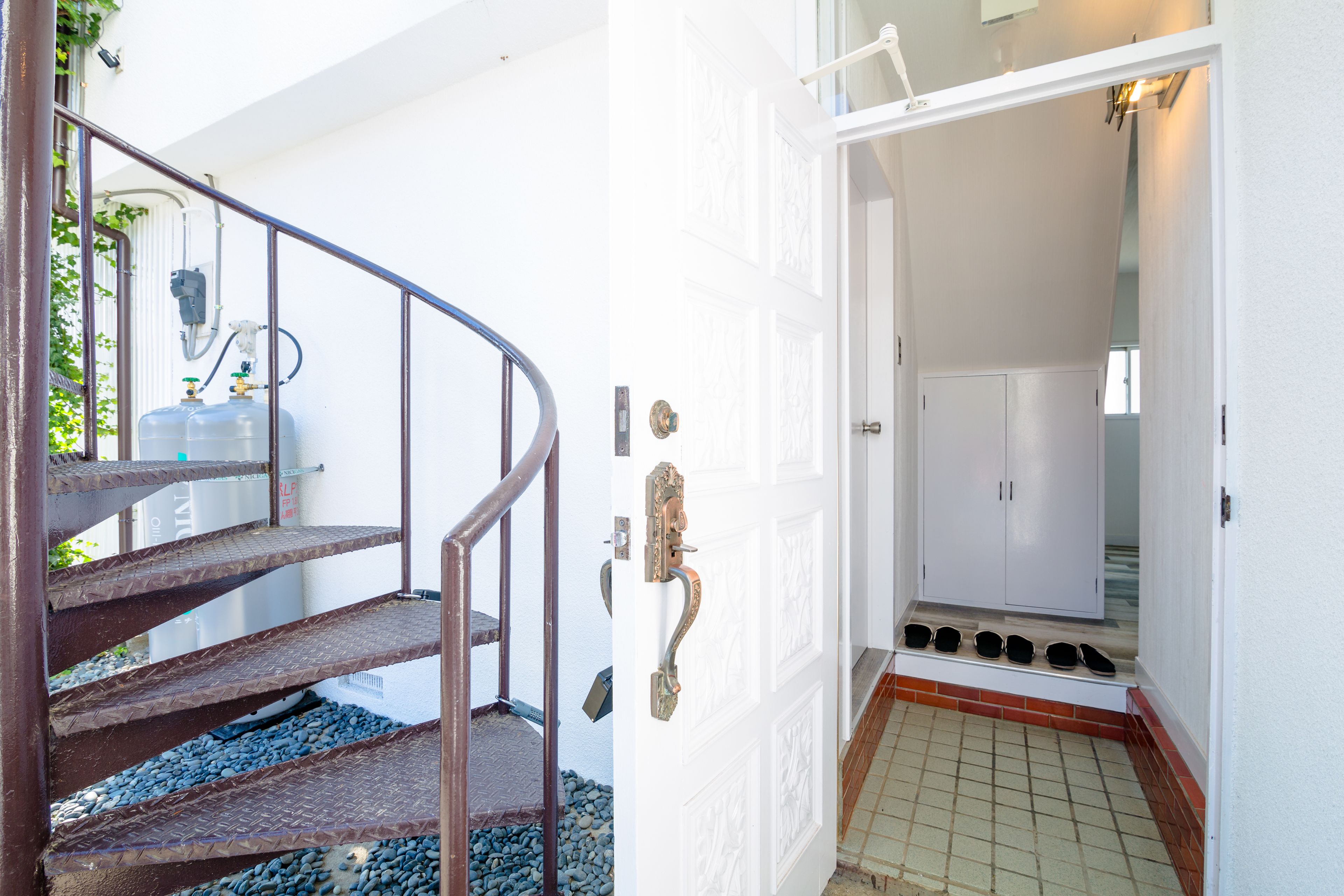 A spiral staircase with metal railings leading to a white door with a brass handle.