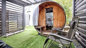 A wooden barrel-shaped structure with a bench and a table inside, surrounded by a wooden fence and a grassy area. - tocoro. Mt. Fuji Hazuki (Fujikawaguchiko)