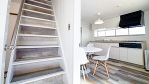A modern kitchen with white cabinets, a black range hood, and a dining area with white chairs and a small table. - tocoro. Mt. Fuji Hazuki (Fujikawaguchiko)