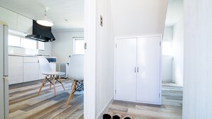 A modern kitchen with white cabinets, a black range hood, and a wooden dining chair. - tocoro. Mt. Fuji Hazuki (Fujikawaguchiko)