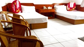A hotel room with two beds, a wooden nightstand, a chair, and a small table.