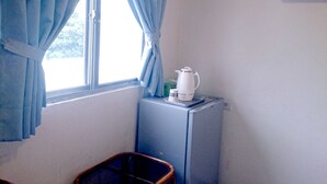A small room with a window, a radiator, a kettle, and a chair. - Jin Lon Hotel (Taitung)