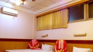A hotel room with two single beds, a window with curtains, an air conditioning unit, and a wooden floor. - Jin Lon Hotel (Taitung)