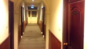 A long, narrow hallway with a carpeted floor and wooden doors on both sides. - Jin Lon Hotel (Taitung)