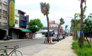 A street with palm trees, parked bicycles, and motorcycles.