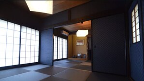 Ein traditioneller japanischer Raum mit Tatami-Bodenbelag, Schiebetüren und einer niedrigen Decke.