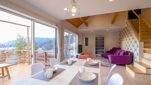 A modern living room with a wooden dining table set for four, a purple sofa, and a staircase with wooden railings. - tocoro. Mt. Fuji Mutsuki (Fujikawaguchiko)