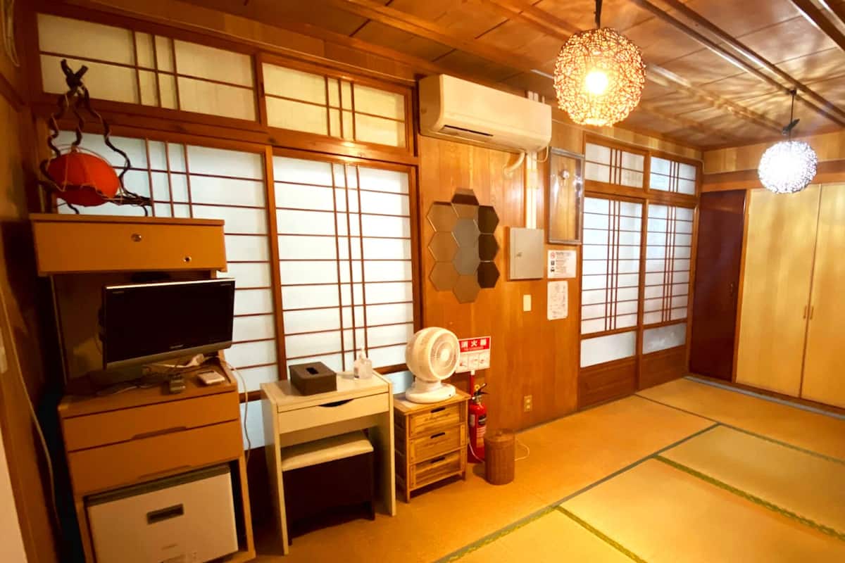 Una habitación japonesa tradicional con suelo de tatami, un televisor, un escritorio y una puerta corredera.