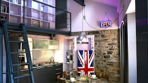 A compact kitchen with a dining area, a flag decoration, and a neon 'OPEN' sign.