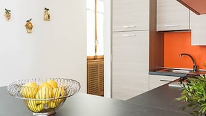 A modern kitchen with white cabinets, a glass bowl of fruit on the counter, and a plant in the corner. - Cernobbio Lake View (Cernobbio)