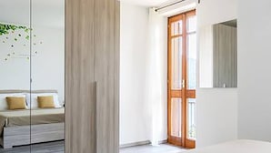 A bedroom with a bed, a wardrobe, and a door leading to a balcony. - Cernobbio Lake View (Cernobbio)