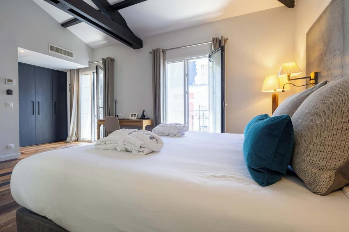 A hotel room with a large bed, a desk, and a view of the outside.